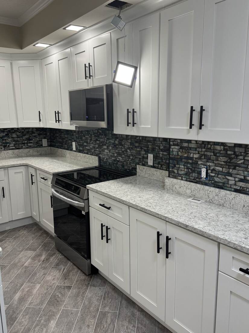 Remodeled kitchen with white cabinets and tile backsplash