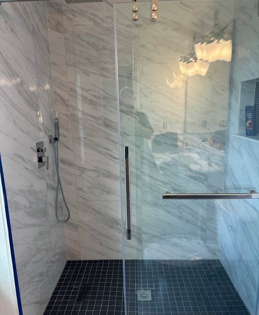 Carrara marble shower with glass enclosure